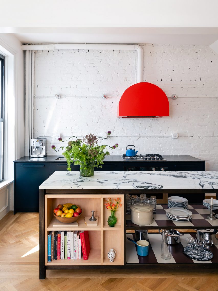 Kitchen with marble-topped island and bright red cooker hood