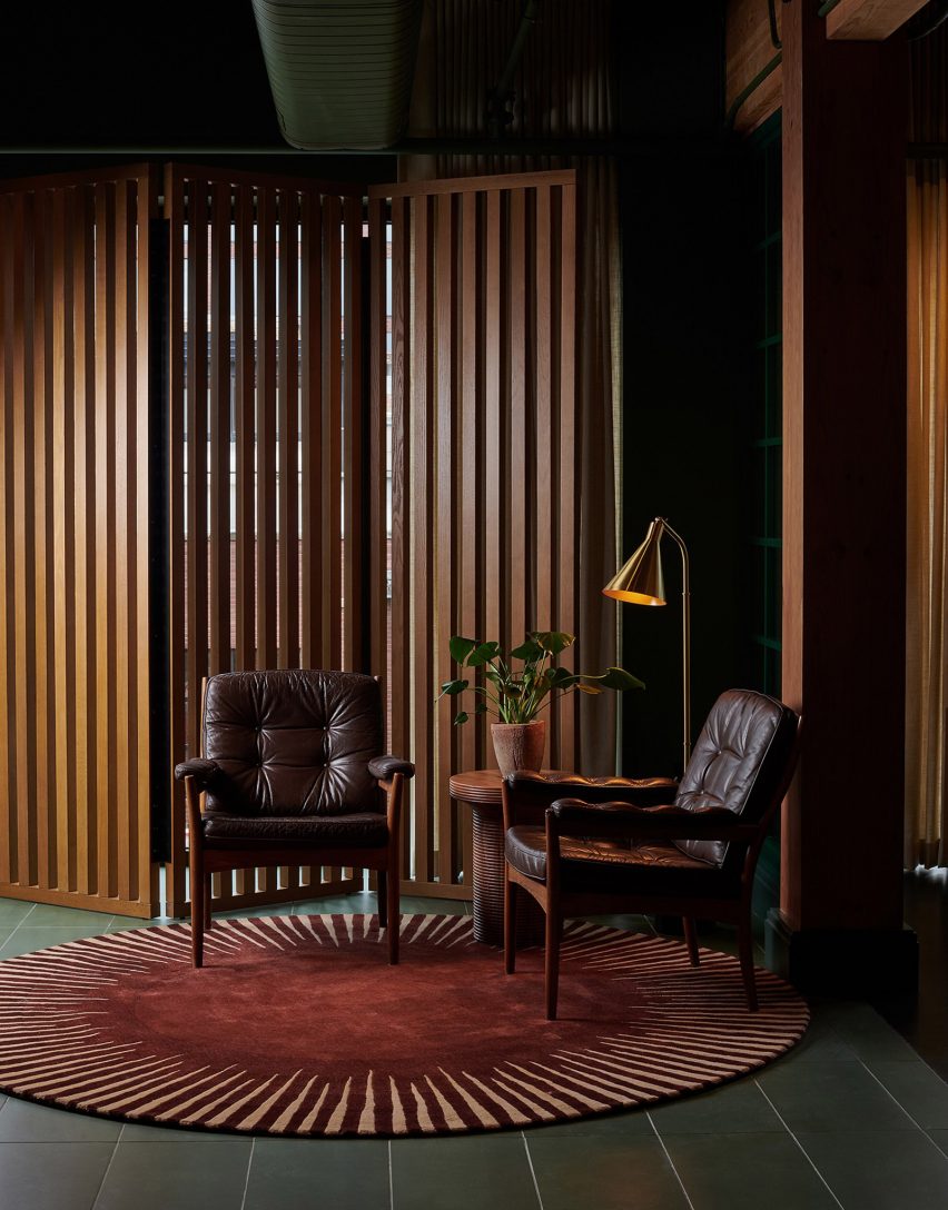 Lobby seating area of members' club by AvroKO with leather armchairs and slatted wooden screen