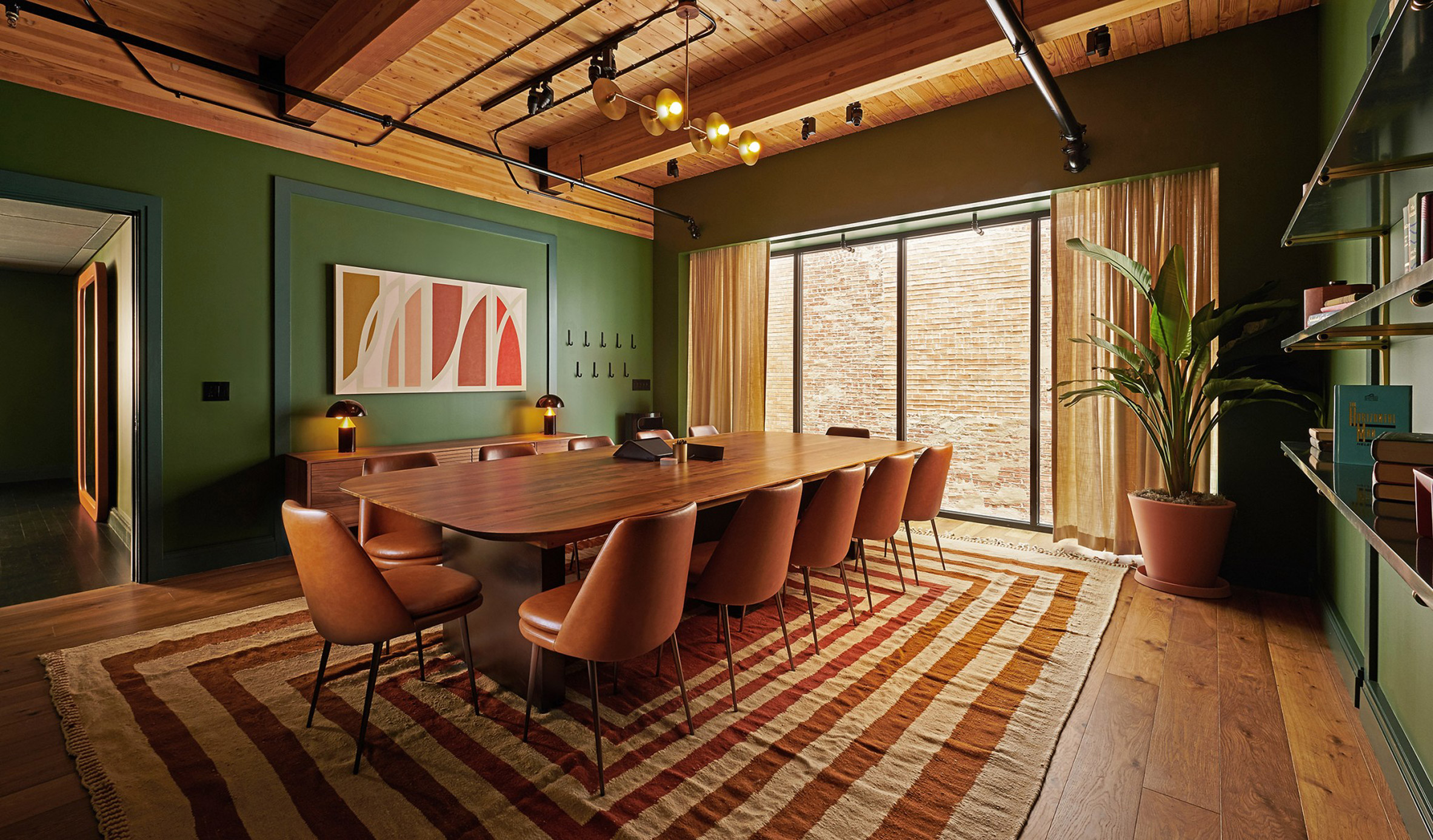 Meeting room in Chief Chicago clubhouse with long wooden table, leather chairs and geometric pattern rug