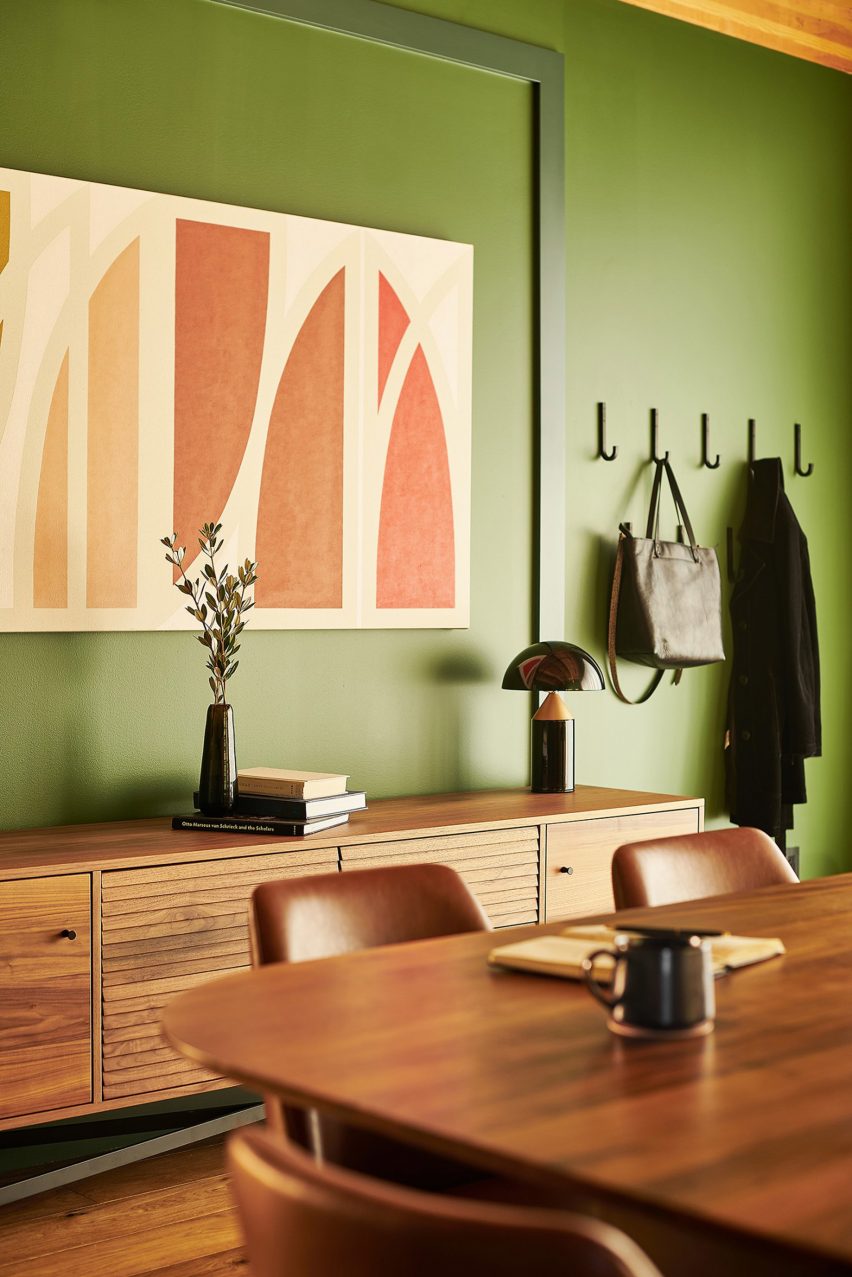 Meeting room interior by AvroKO with wooden table, green walls and abstract artwork