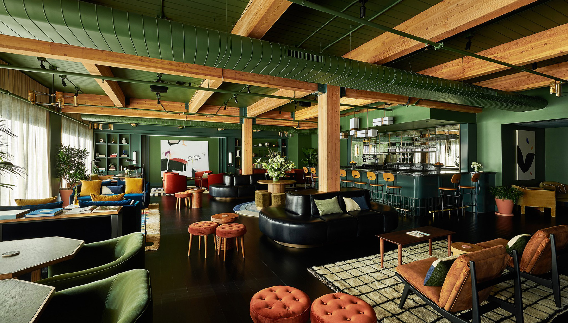 Lounge of Chief Chicago clubhouse with exposed timber beams, green walls and multicoloured seating