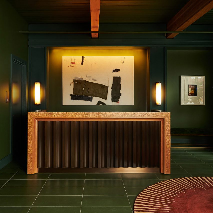 Reception desk with black corrugated base in dark green lobby of Chief Chicago