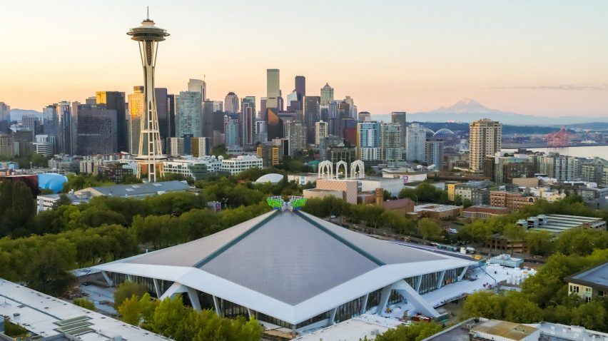 Exterior view of the Climate Pledge Arena in front of the Seattle skyline