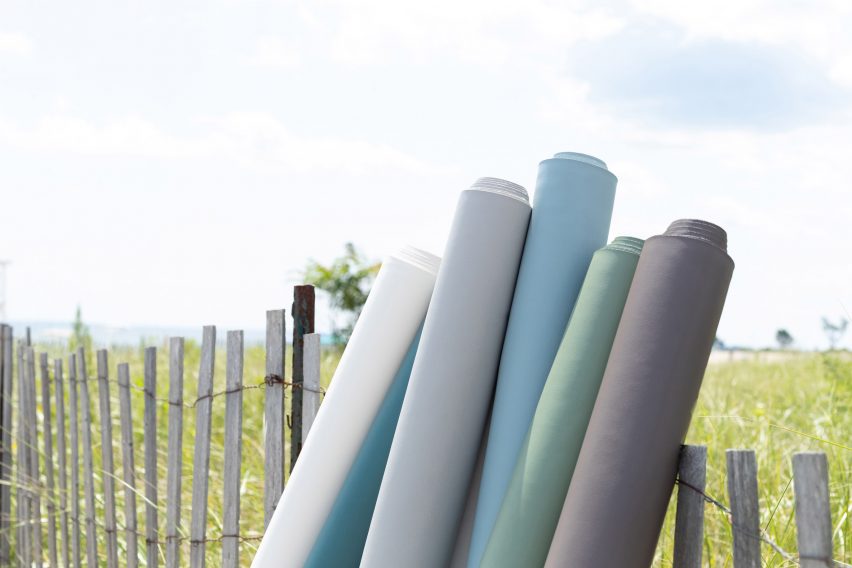 Gulungan kain Pesisir Ultrafabrics dengan warna biru, hijau dan putih bertengger di pagar