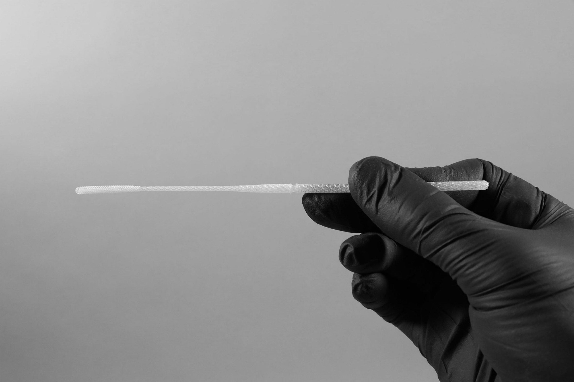 Gloved hand holding a swab for medical testing