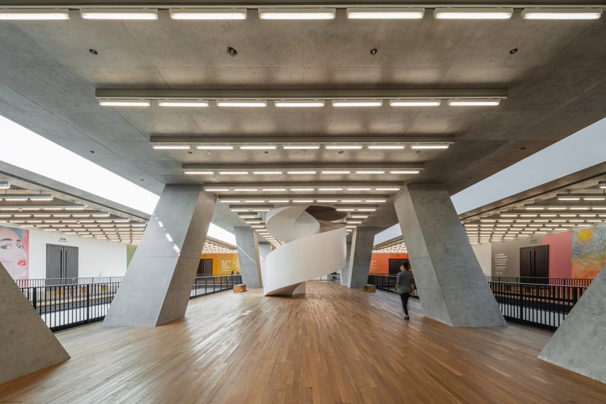 Atrium di lantai dua Museum M+ dengan lantai kayu dan rangka serta langit-langit beton