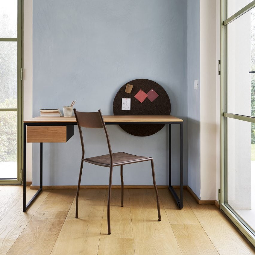 Foto meja Macis dari kayu, diletakkan di dinding biru dengan kursi di depan