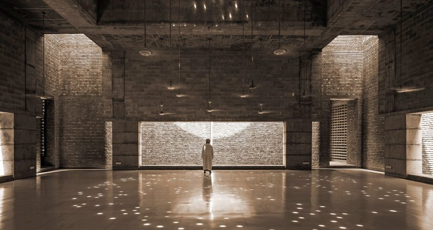 Inside the Bait Ur Rouf Mosque prayer hall with sun-dappled light coming in through the brickwork
