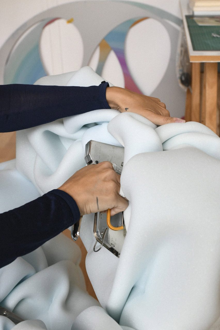Woman stapling light blue upholstery onto a chair for Massproductions' Face Lift network