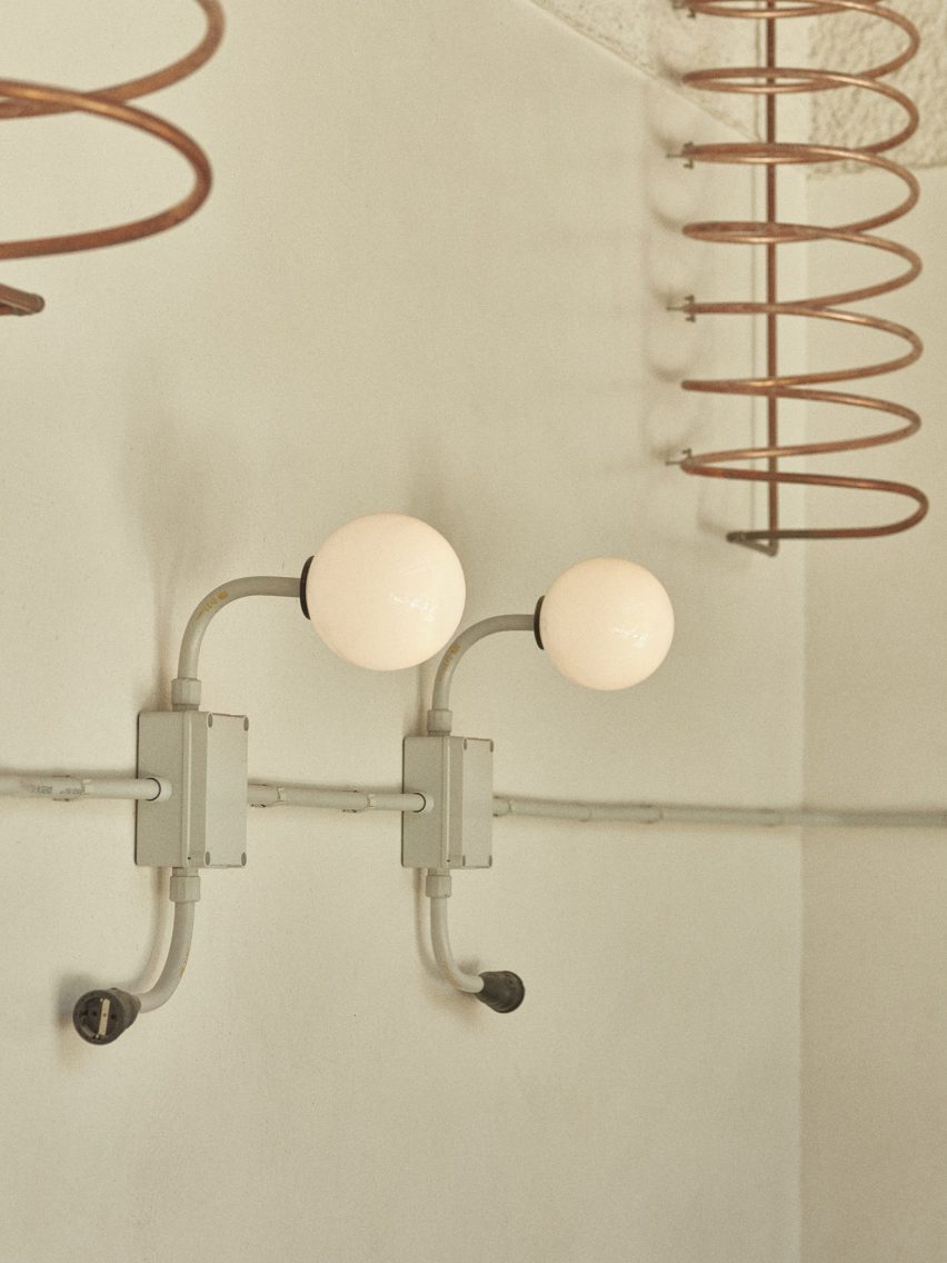 Copper spiral radiator and round bulb light fixture on a smooth grey wall