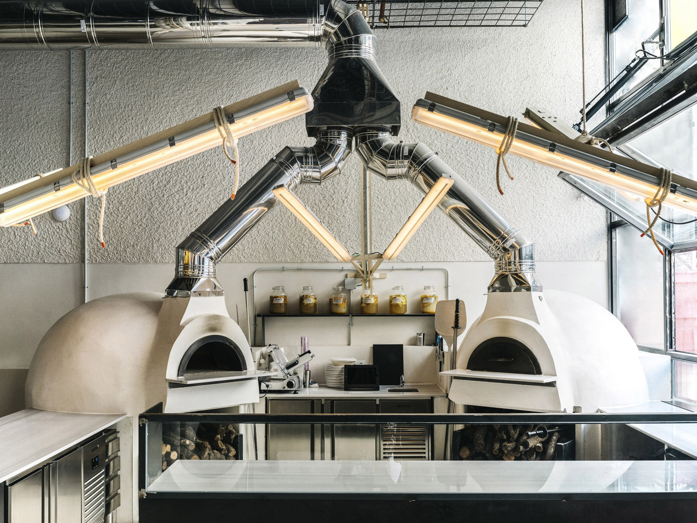 Pizza ovens in a restaurant kitchen hooked up to wiring with lighting rods overhead