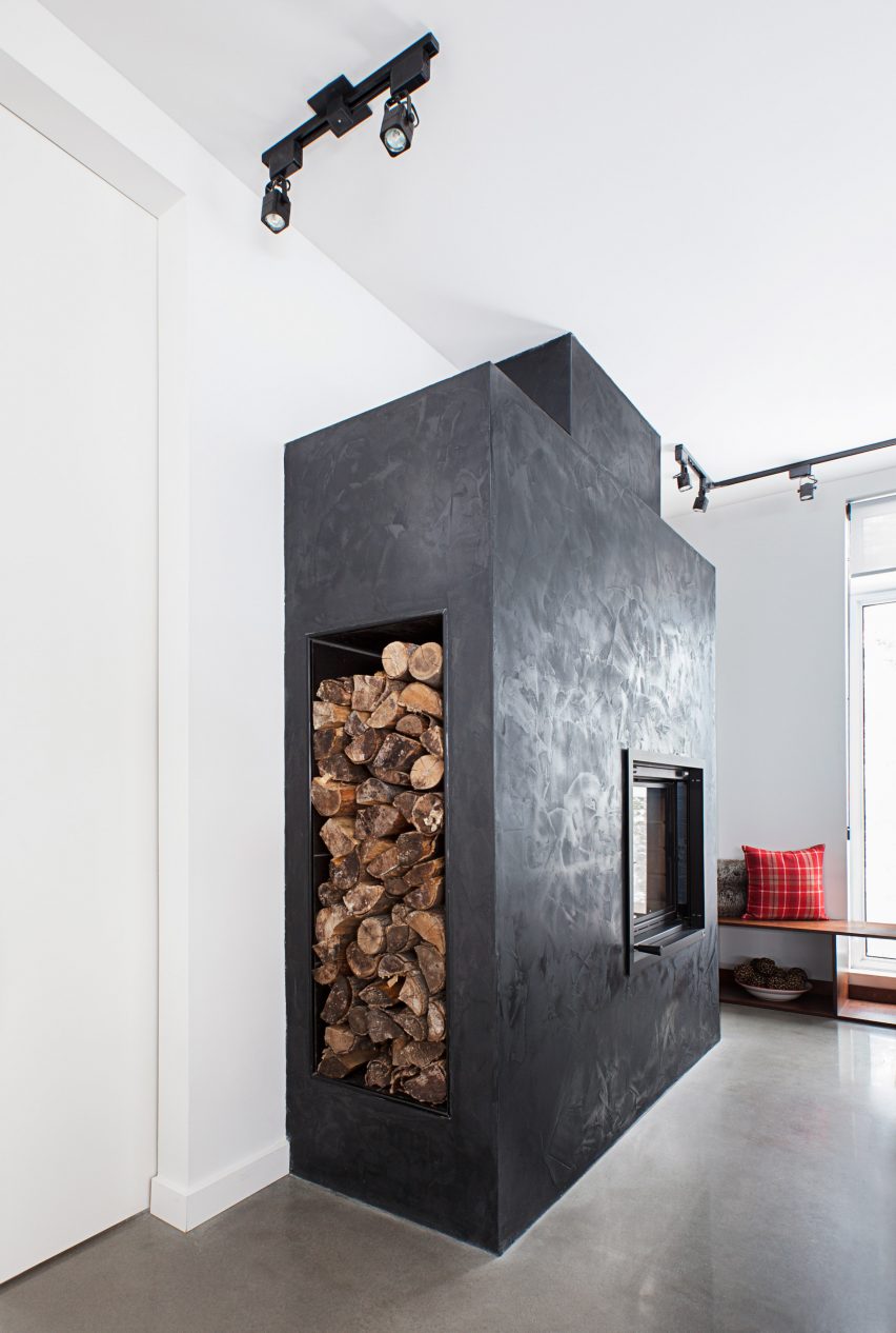 Image of a black concrete fireplace with chopped wood storage