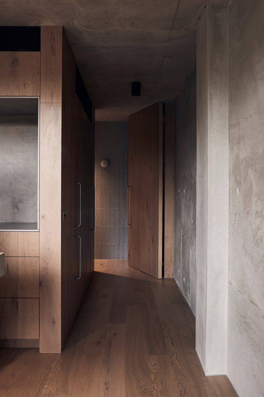 Lorong dengan dinding beton dan lantai kayu ek di interior hunian oleh oleh Studio Goss