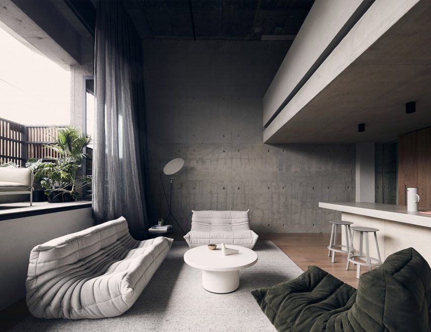 Ruang tamu cekung dengan tempat duduk Togo, dinding beton, dan dapur terbuka di apartemen Roseneath Street