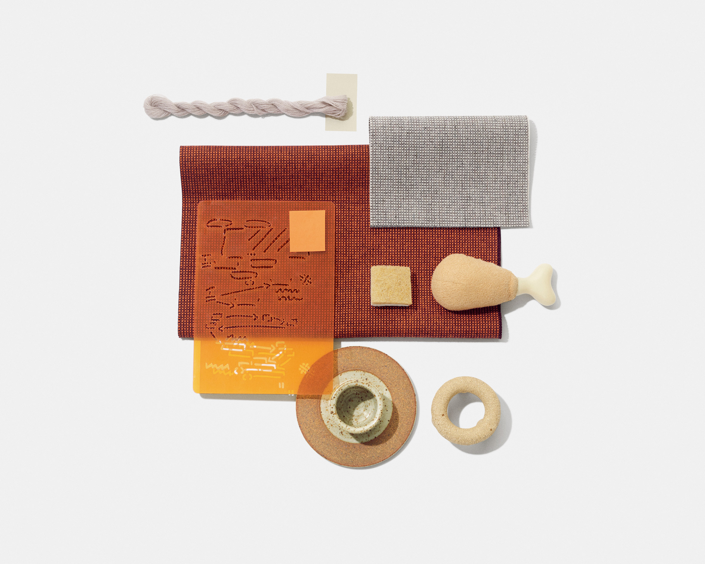 Swatches of Kvadrat's Sabi textile upholstery in a deep orange colour with similarly coloured objects