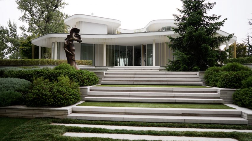 Curved white villa with wraparound windows surrounded by trees