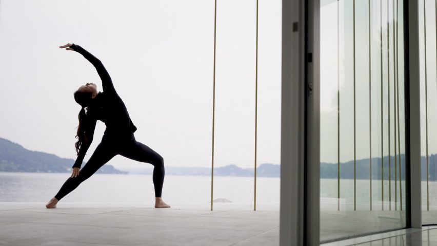 Dara Huang does yoga in front of a floor-to-ceiling window with views of a lake and sky