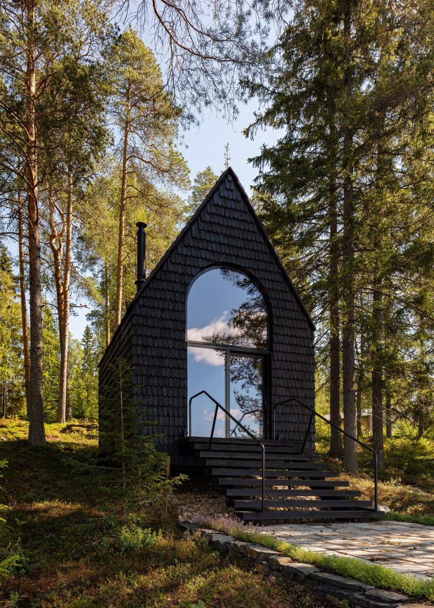 Woodland cabin covered in black shingles