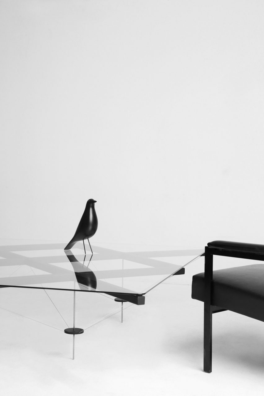TT_01 table with a black decorative bird sitting on top and a black armchair beside it