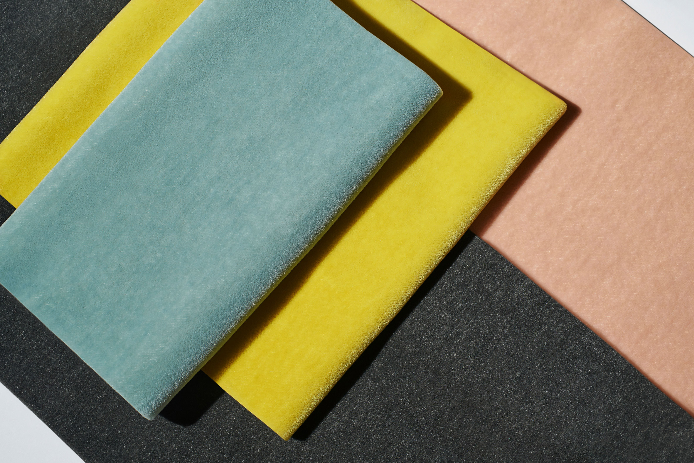 Dedar's Vladimiro velvet laid out in sheets of different colours including yellow and light blue