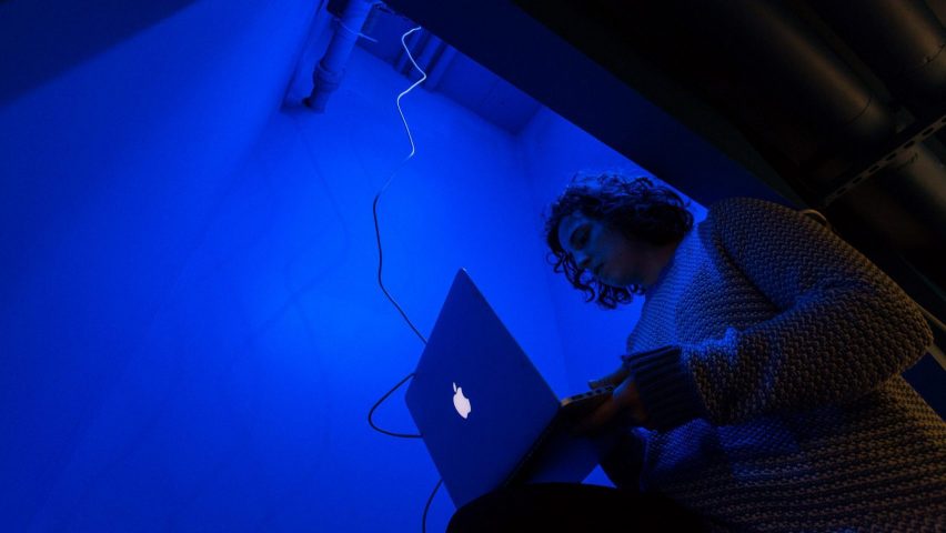 Студент в комнате с синим освещением работает на ноутбуке