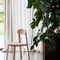 A photograph of the Brulla chair in natural ash in front of draped curtains