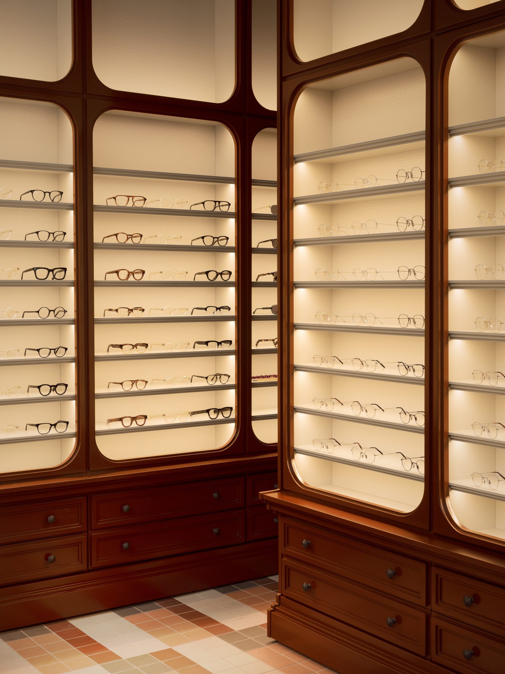 Glass displayed in backlit Victorian-style cabinetry in eyewear store by Child Studio
