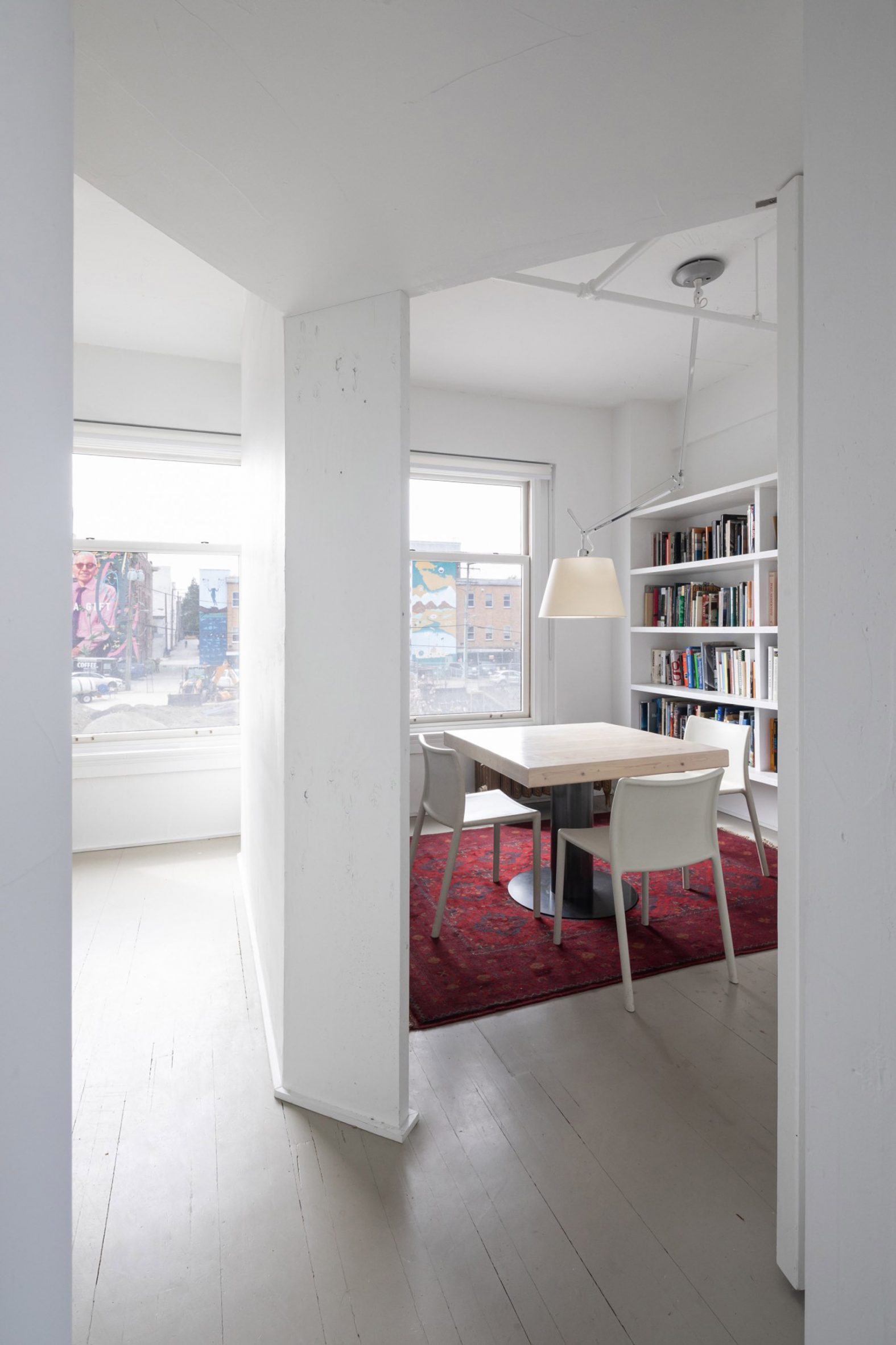 Small meeting room with white-painted wooden floors and white shelving in D'Arcy Jones Architects' self-designed studio