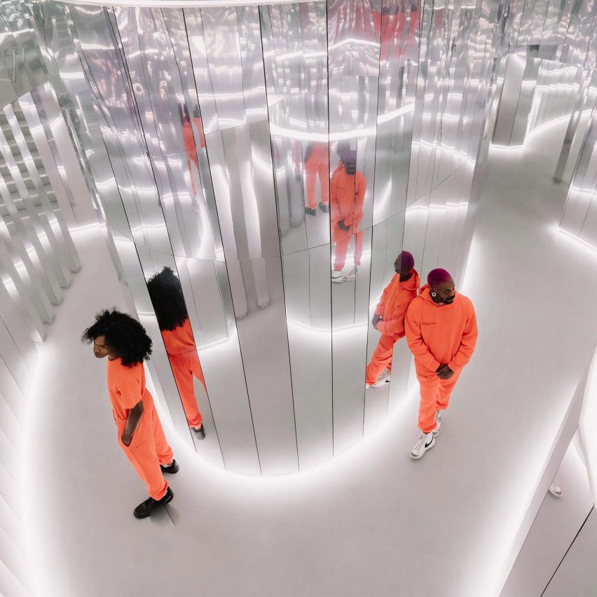 Models wearing orange clothes inside a mirrored Es Devlin installation
