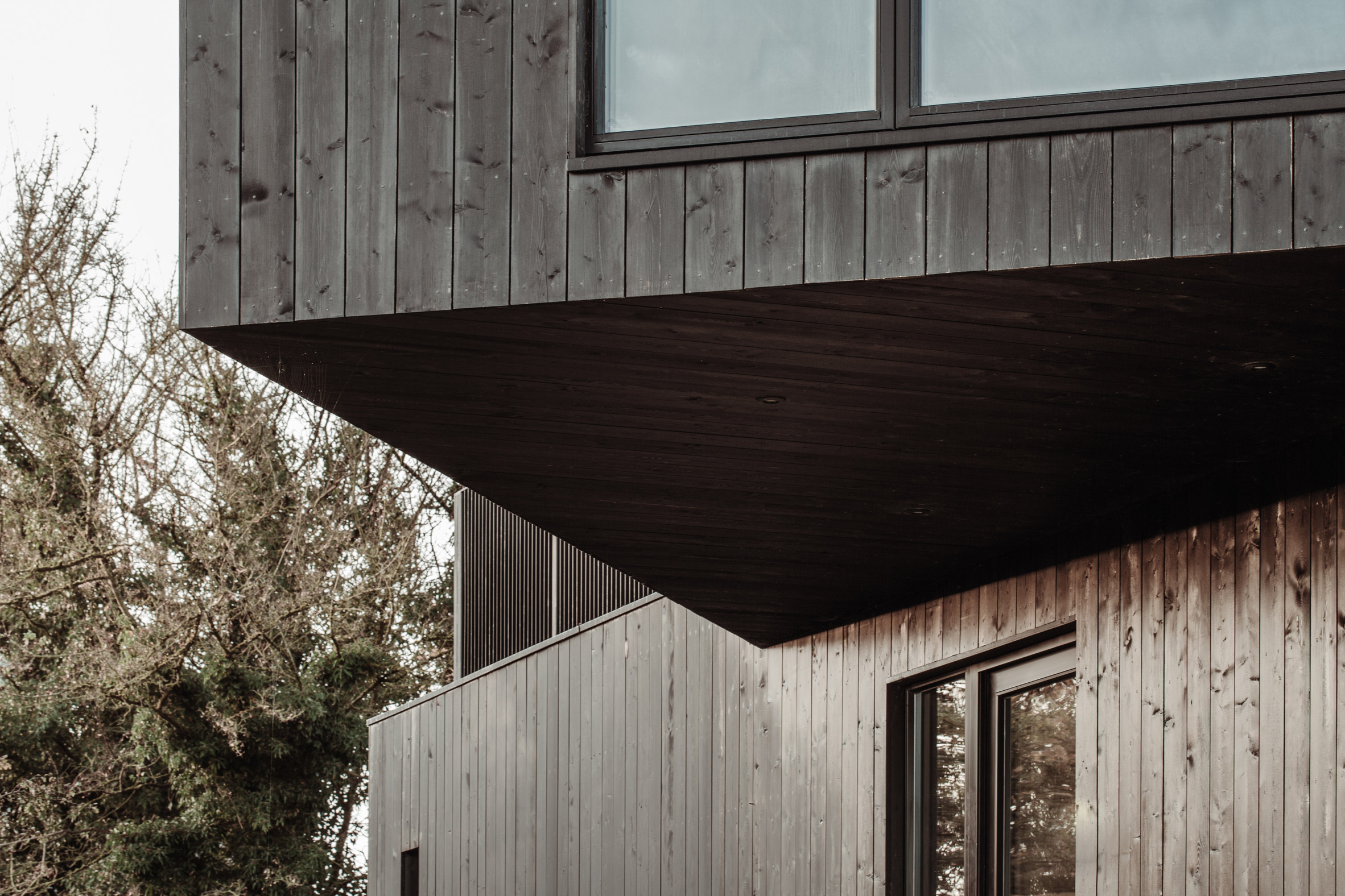 A black structure cantilevers over a cabin