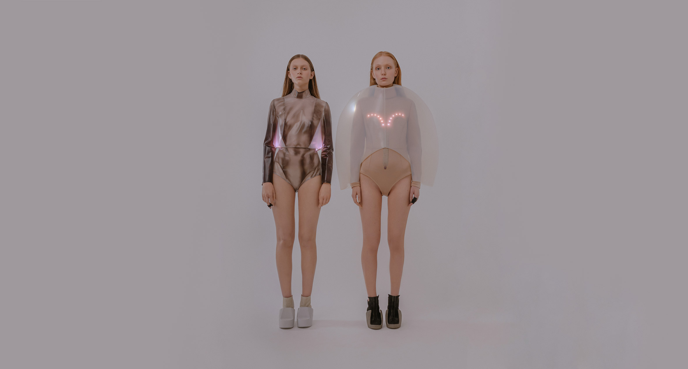 Two models stand next to each other wearing tops with LED lights