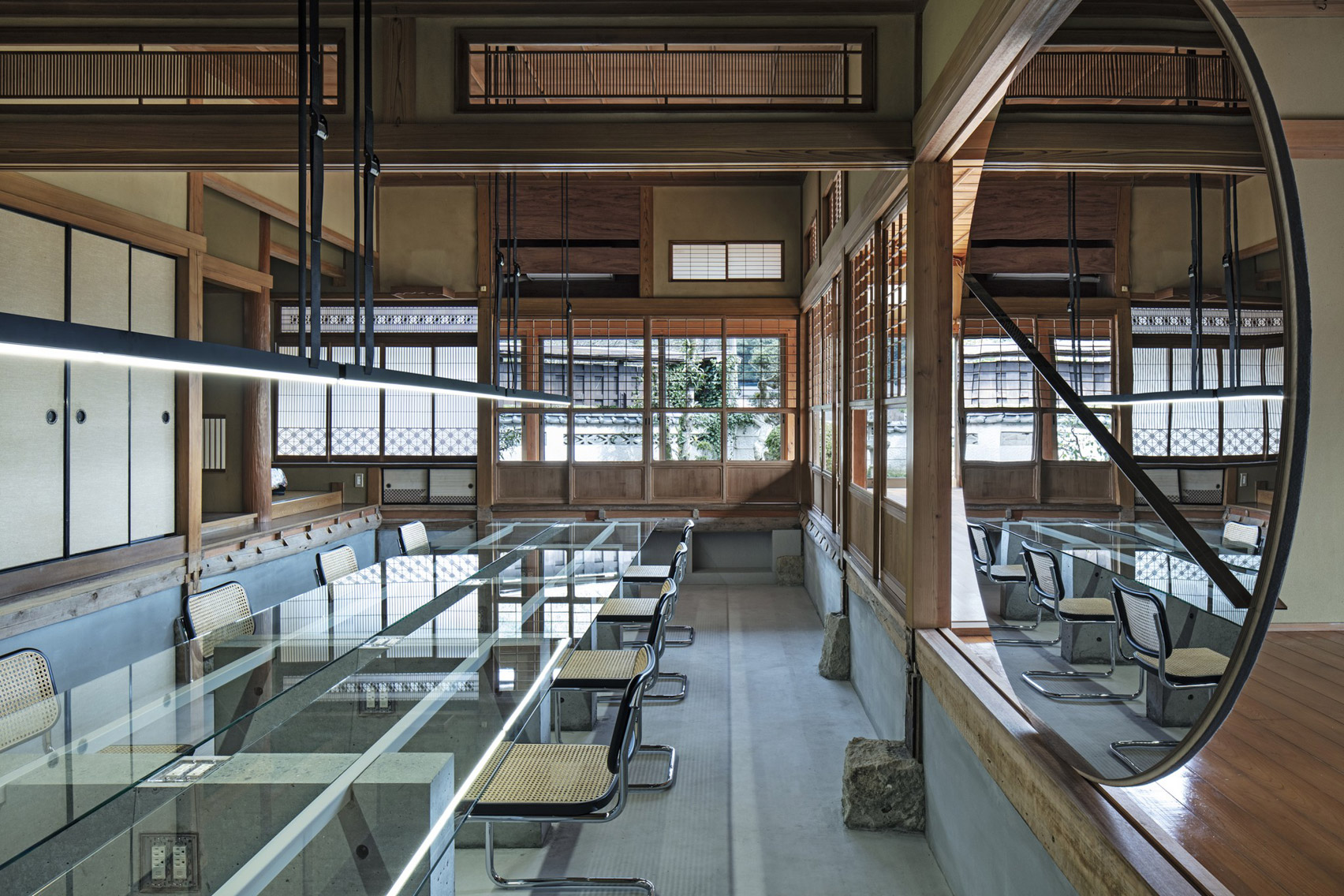 Workspace with long glass table and rattan hairs in Maruhiro office