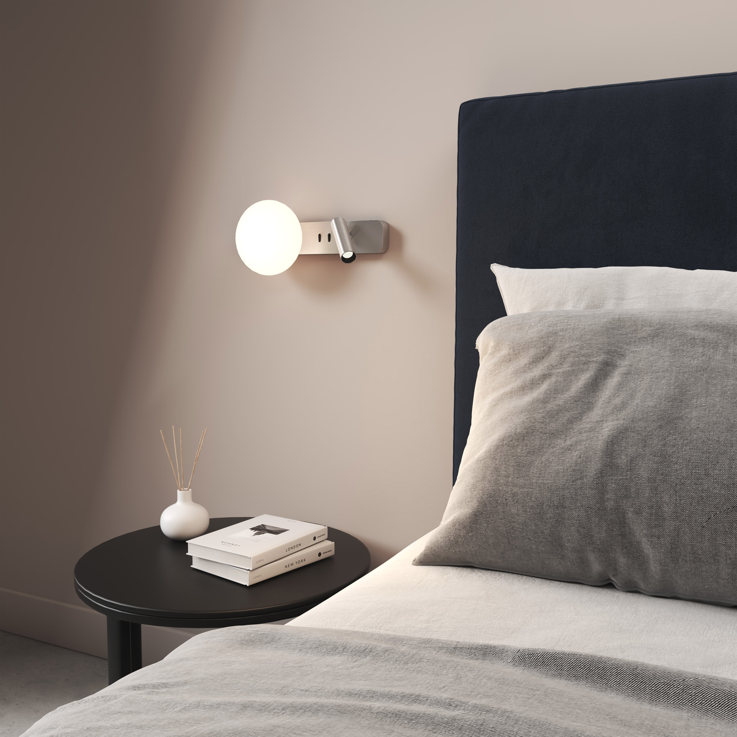A photograph of a circular Reader edit light, which was presented on Dezeen Showroom, mounted on a wall next to a bed