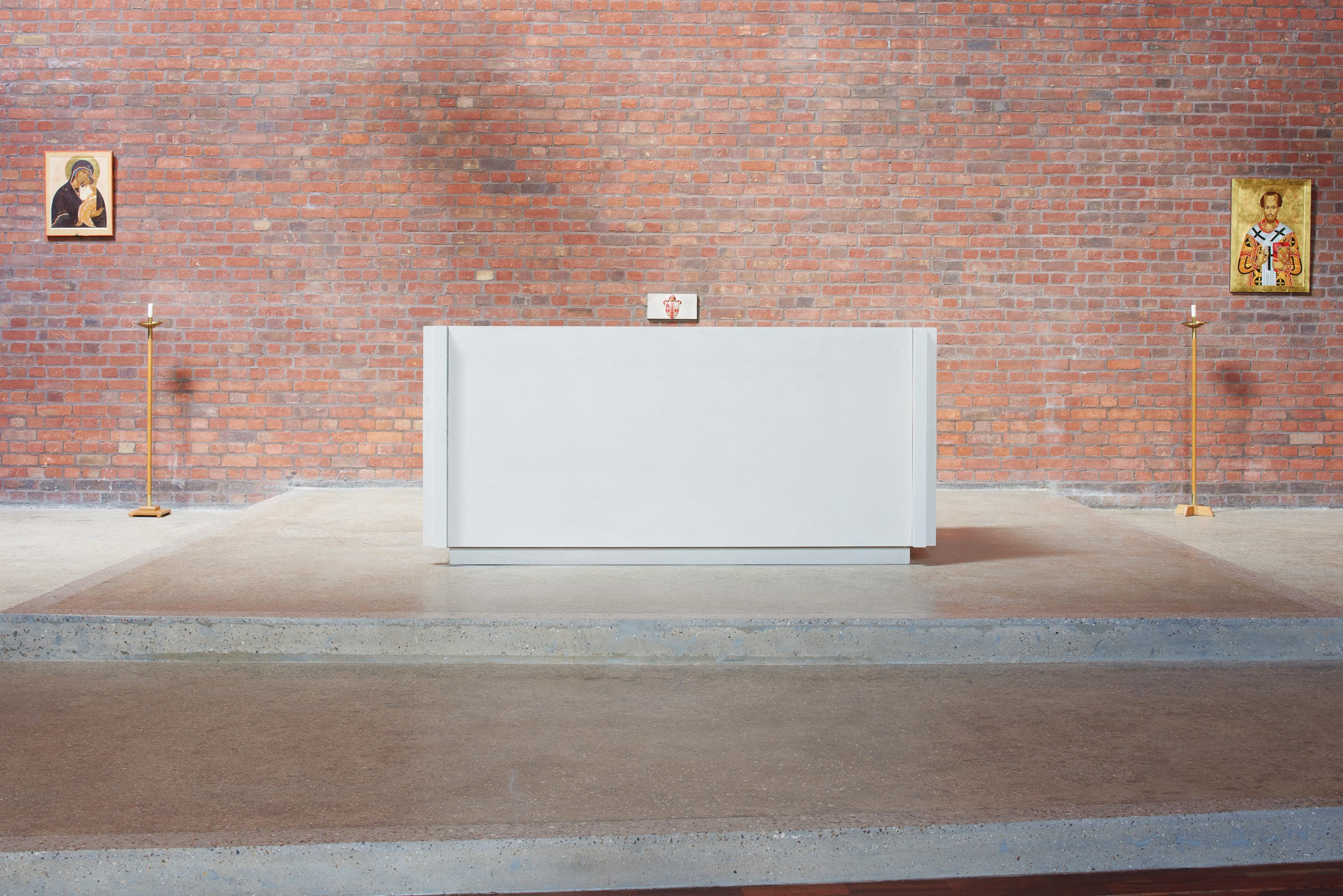 White monolithic altar made of Portland limestone in a red brick walled church