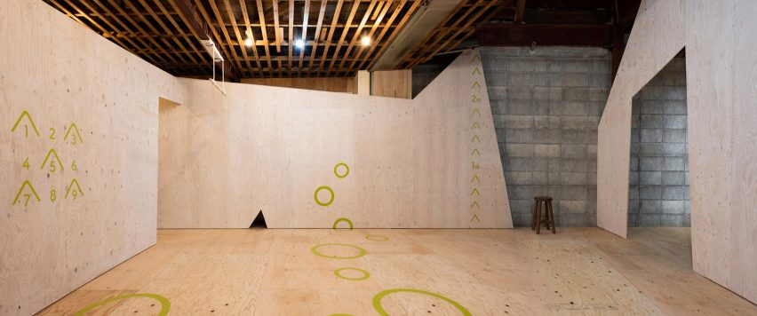 Lantai dan dinding kayu lapis dengan tanda hijau di pusat pekerjaan Yoridoko di Jepang