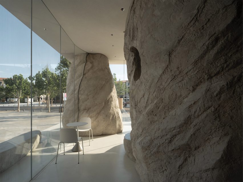 White table and chairs at Zolaism Café next to a glass wall and surrounded by rock-shaped columns