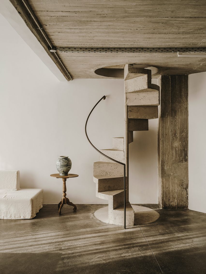 Concrete spiral staircase next to side table with vase in Athens venue by Studio Andrew Trotter