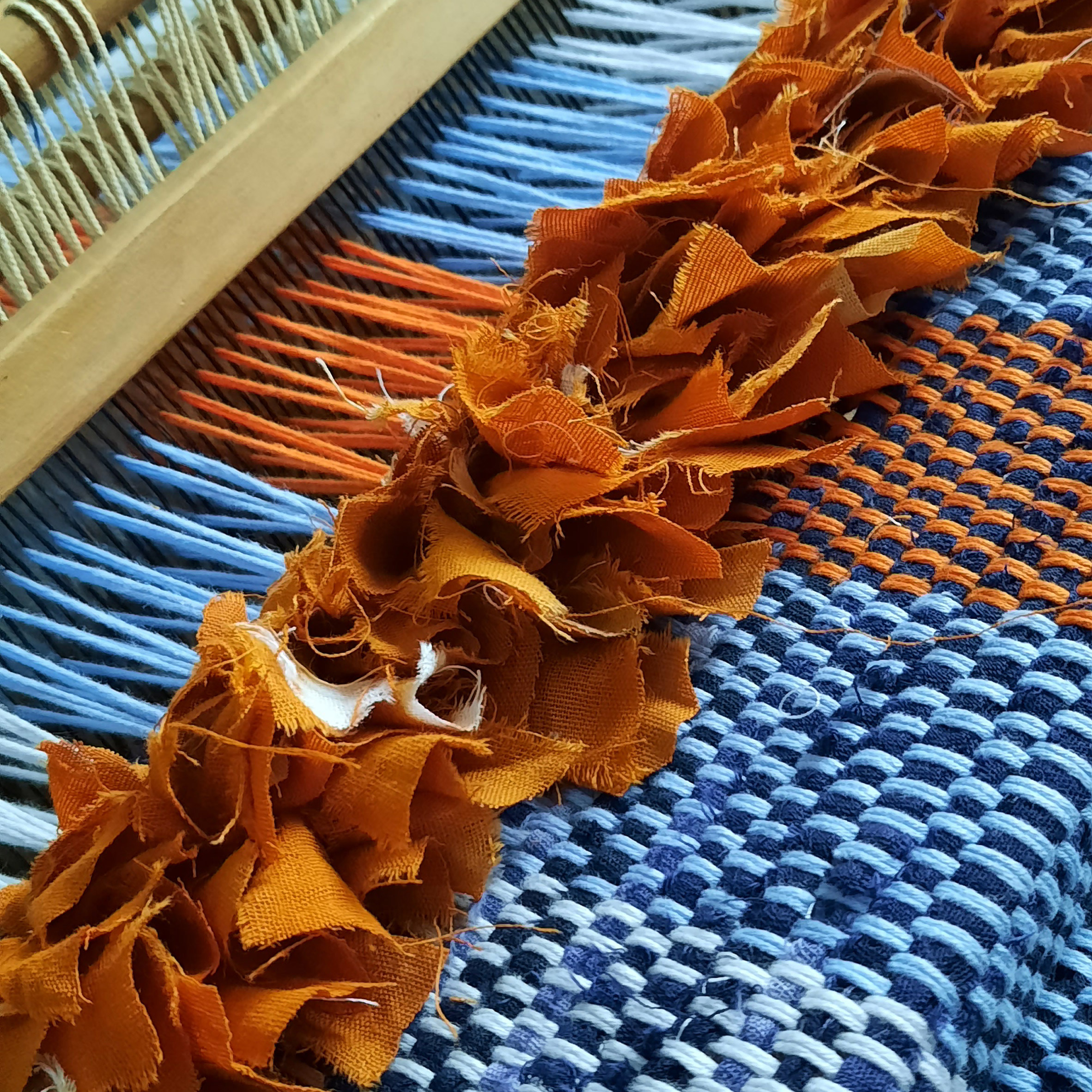 Close-up of Dakala Cloth weaving process by Nkwo Onwuka using blue and orange yarn