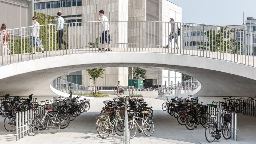 Karen Blixens Plads in Copenhagen by Cobe with bicycle storage and pedestrians passing over a bridge as photographed by Rasmus Hjortshøj illustrating EC proposal on cycling and walking infrastructure