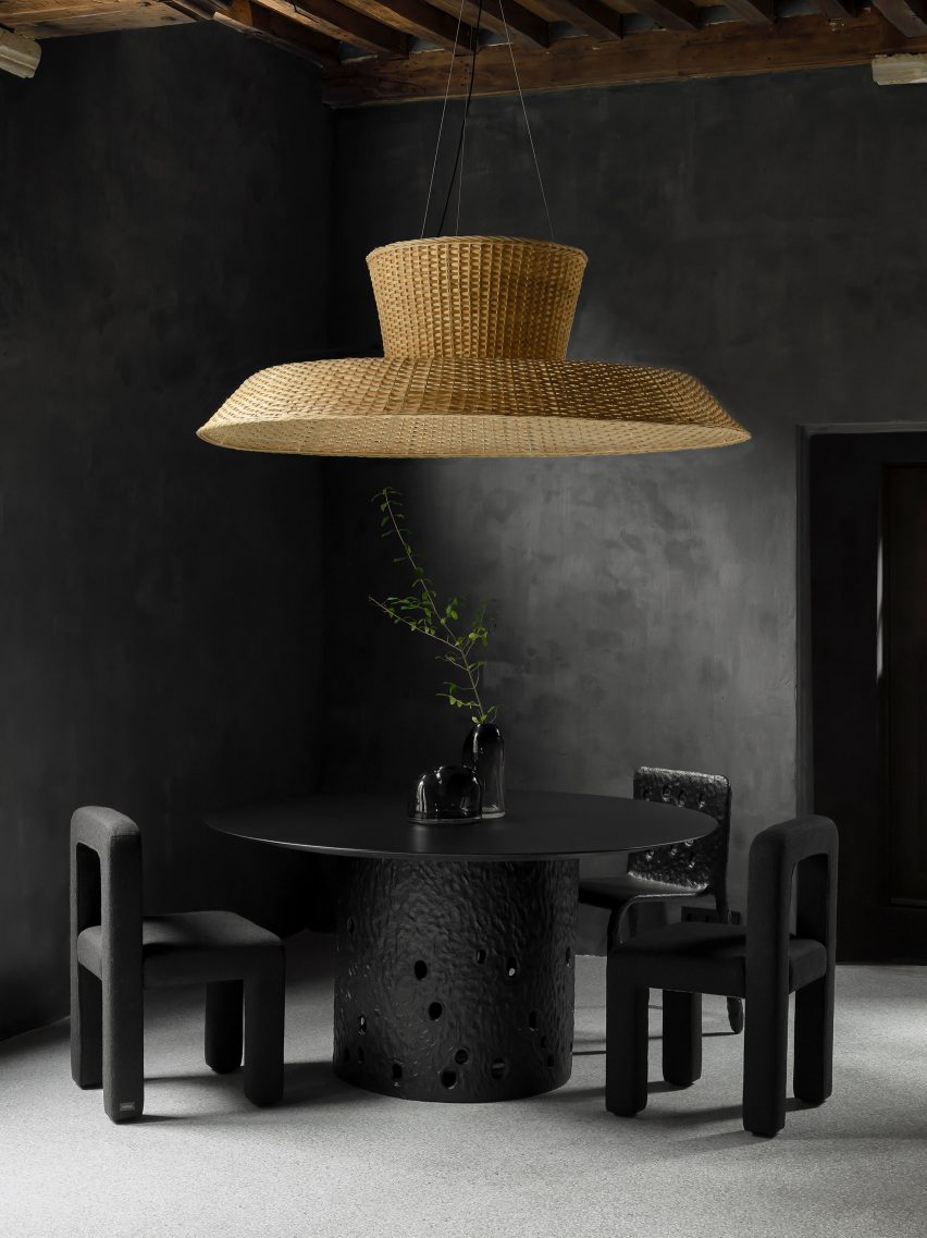Black table and chairs under wicker pendant lamp in Faina Gallery in Antwerp