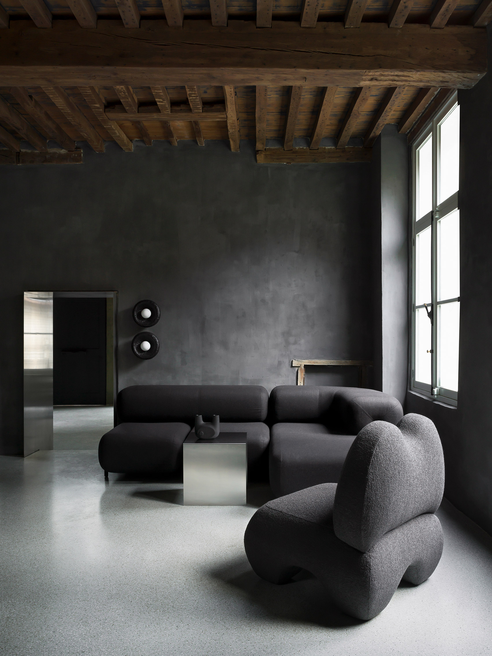 Black-painted room with black sofa and armchair by Faina in Antwerp showroom by Yakusha Design