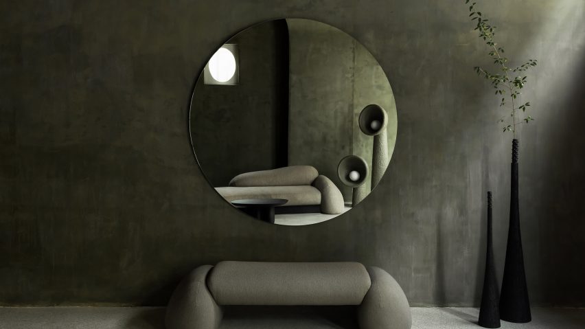 Green-painted room with green Faina couch and circular mirror in Antwerp's Faina Gallery by Yakusha Design
