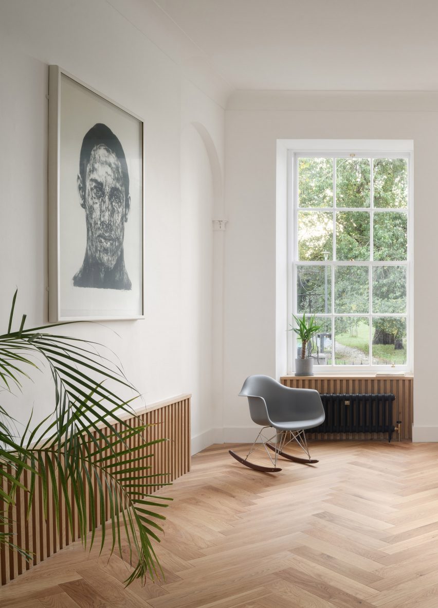 Oak wood panelled living room with parquet flooring and grey rocking chair next to portrait artwork from Leith apartment