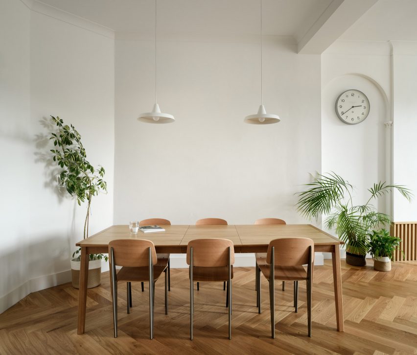 Wooden dining table and chairs surrounded by plants on chevron-pattern parquet flooring in Edinburgh flat by Luke McClelland