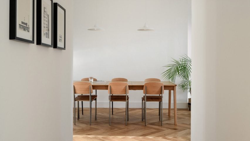 Wooden dining table and chairs on chevron-pattern parquet flooring in Leith apartment designed by Luke McClelland