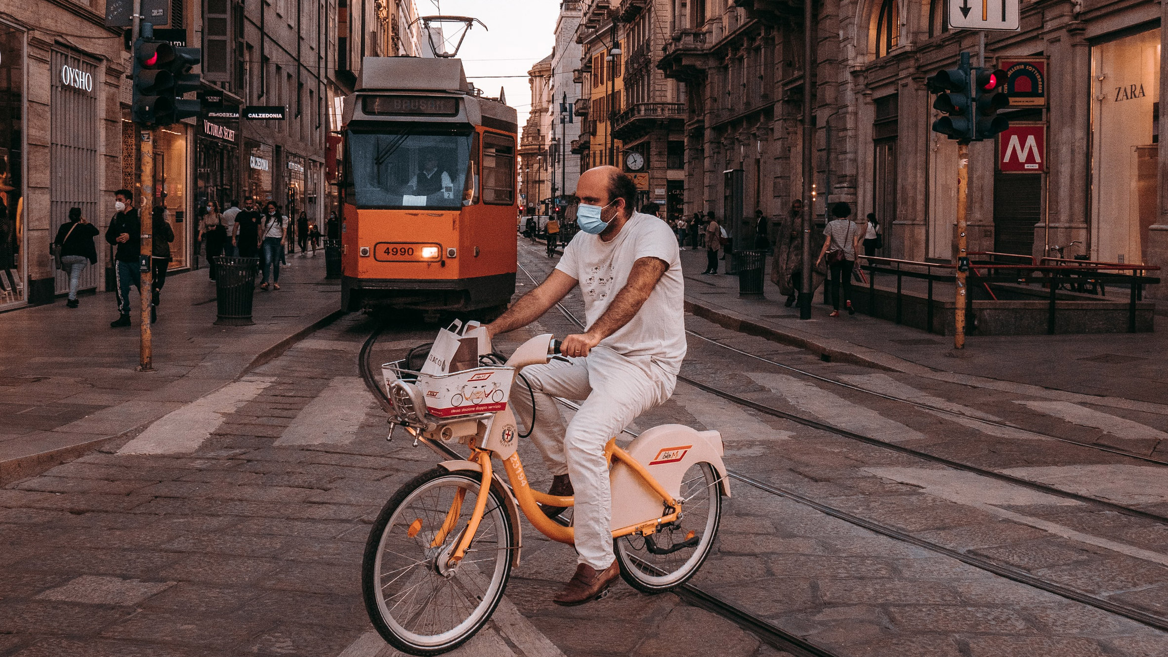 Hombre montando en bicicleta frente a un tranvía en Milán, ilustrando una noticia sobre la red ciclista Cambio planificada en Milán