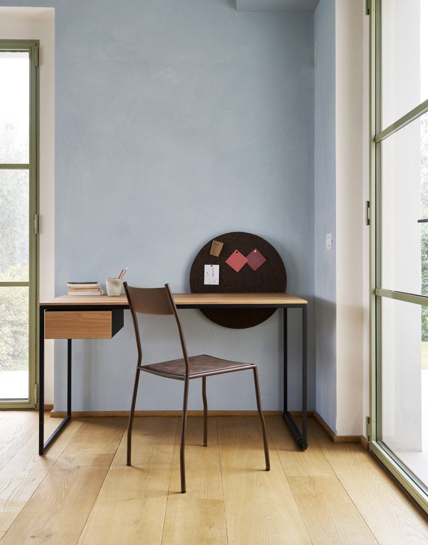 The Macis desk by Opinion Ciatti set against a blue wall with a chair in front.