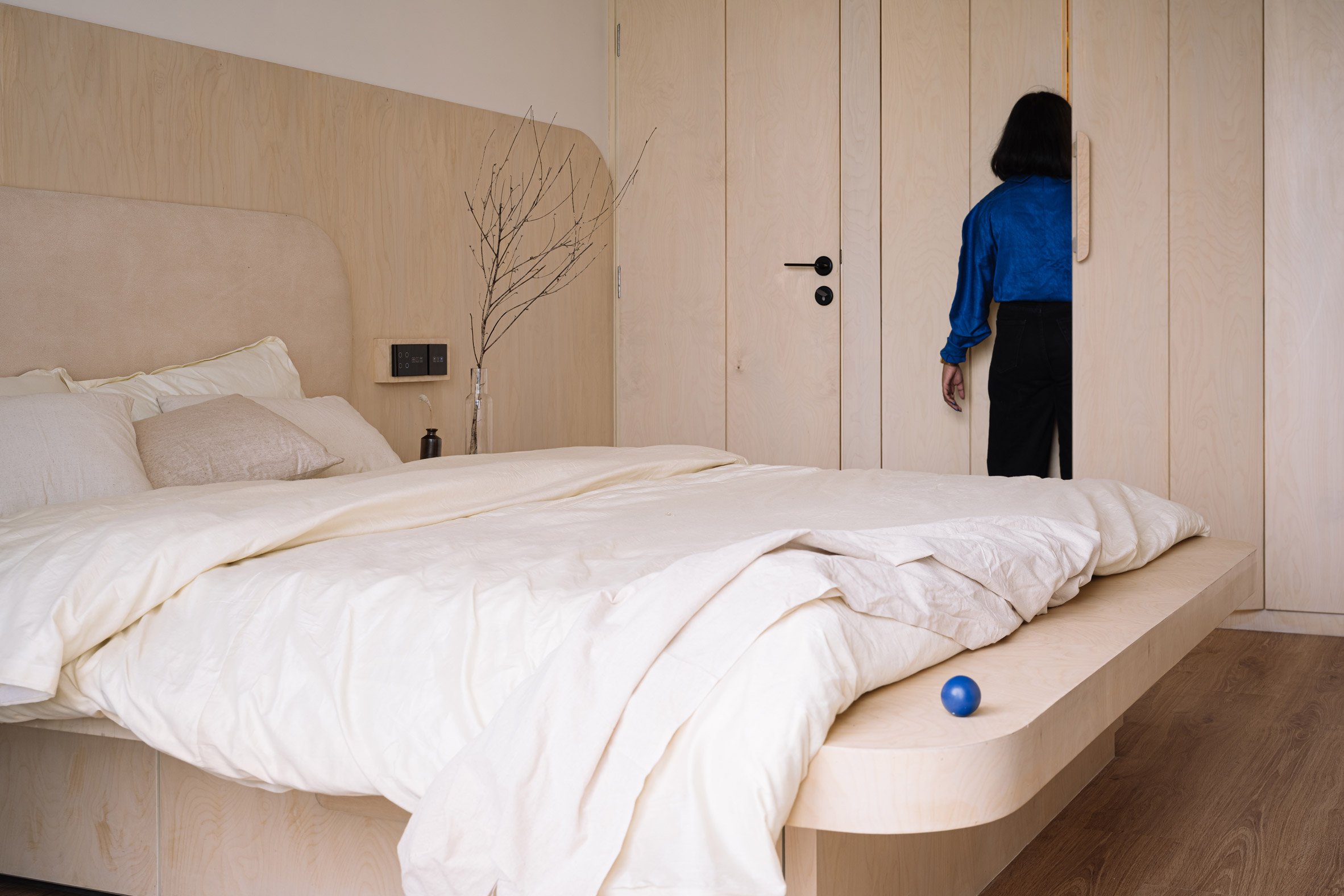 Bedroom of Out of the Blue apartment in India clad with birch plywood bed and built-in storage