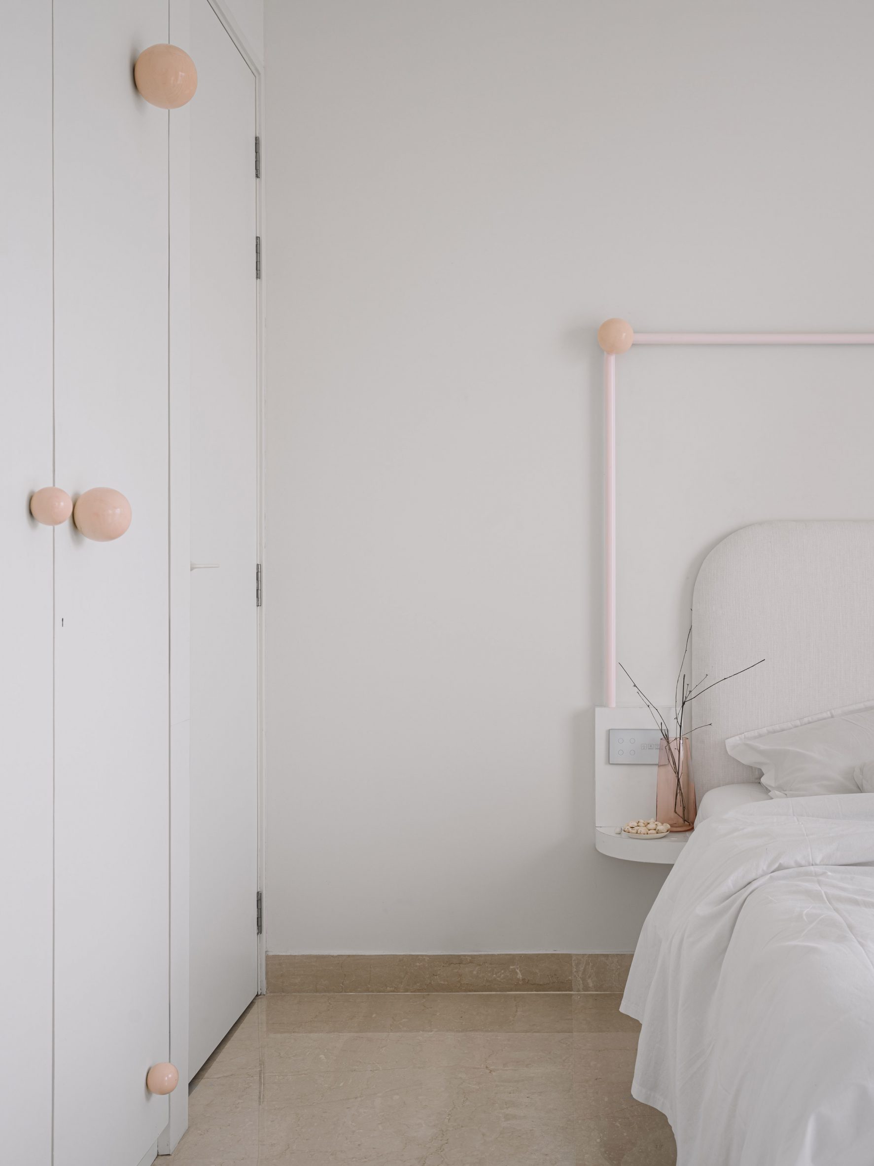 Bedroom interior by The Act of Quad with white wardrobe and bed with pink and peach-coloured accents