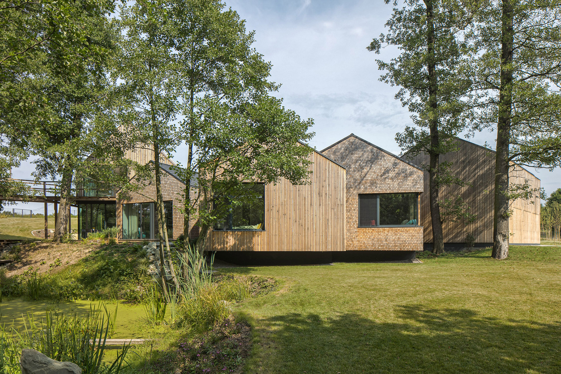 Timber farmhouse with gabled roofs sits in the middle of a green landscape
